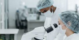 Personas usando microscopio en laboratorio