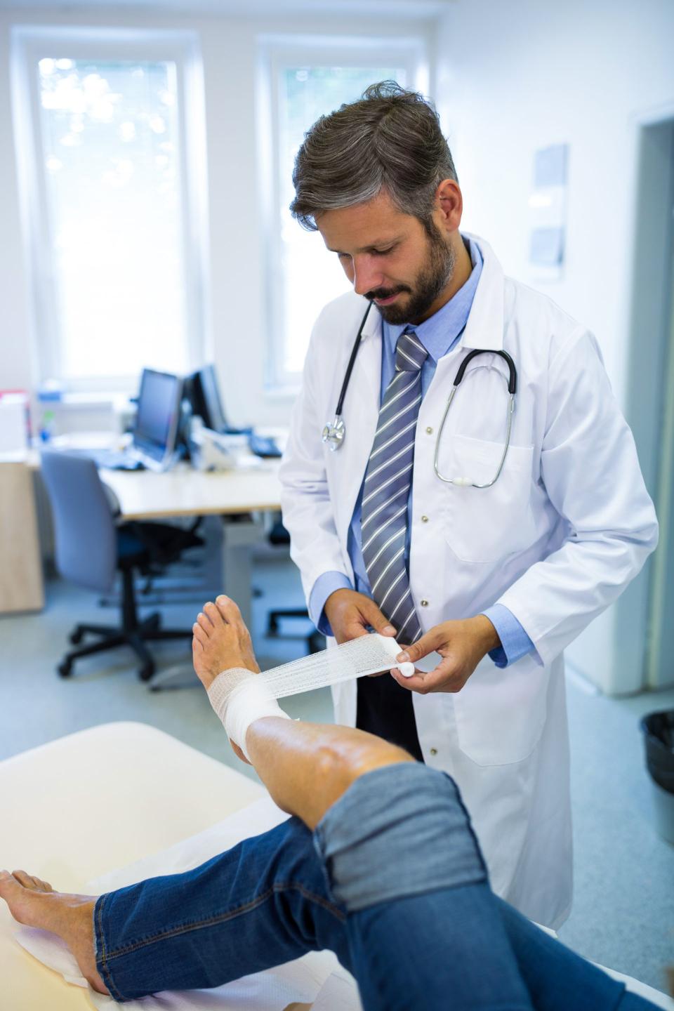 Médico vendando la pierna de un paciente